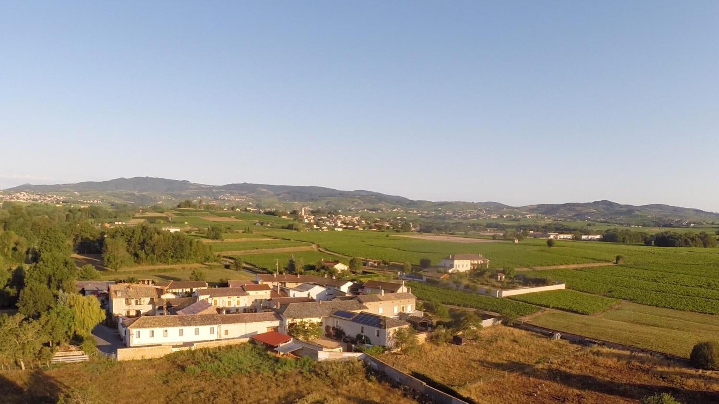 A rural village with traditional houses, fields, and distant hills.