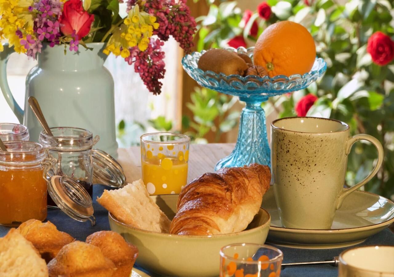Een ontbijttafel met gebak, een croissant, een glas sinaasappelsap en een mok.