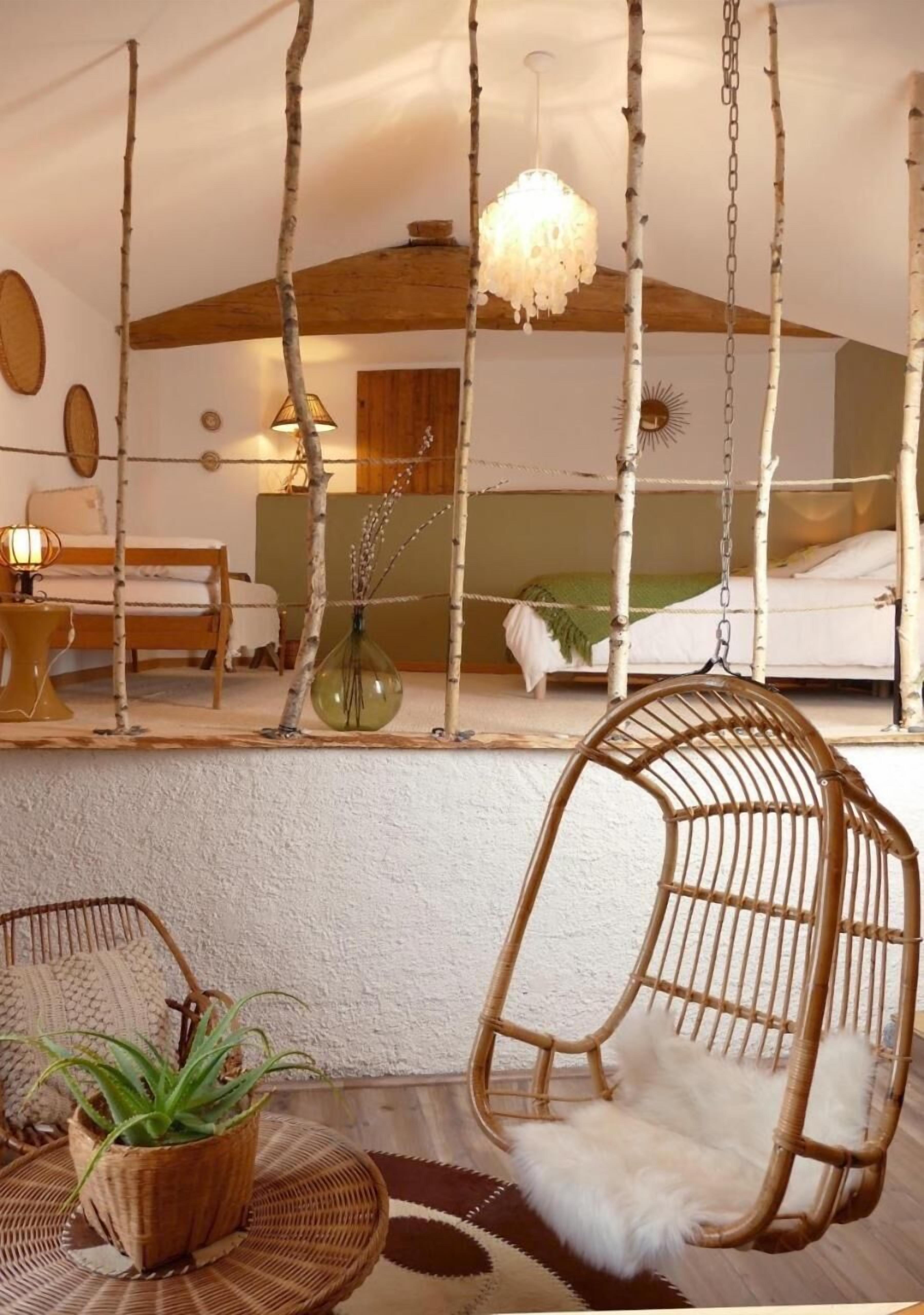 A room with a hanging chair, a bed with a white headboard, and a hanging light fixture.