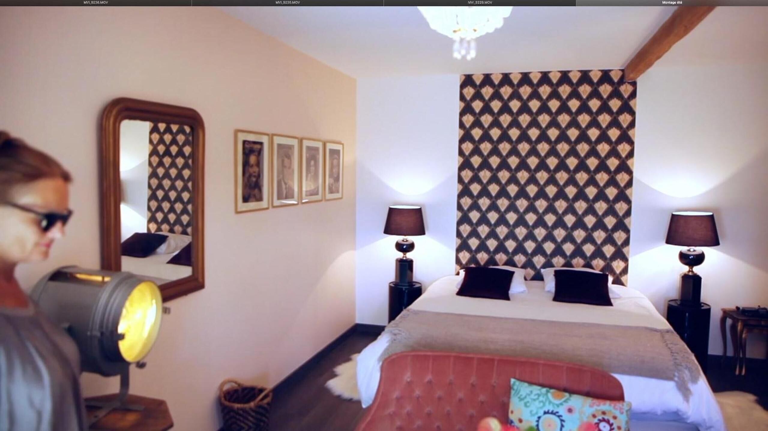 Habitación de hotel con una cama grande, dos lámparas de noche, un espejo y cuadros en la pared.