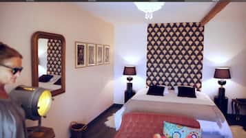 Habitación de hotel con una cama grande, dos lámparas de noche, un espejo y cuadros en la pared.