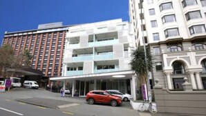 A hotel with a modern facade, multiple floors, and a covered entrance area. - Cosy Renovated 1 Bedroom Apartment in CBD Hotel (Auckland)