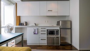 A modern kitchen with white cabinets, a microwave, a refrigerator, and a dishwasher. - Cosy Renovated 1 Bedroom Apartment in CBD Hotel (Auckland)