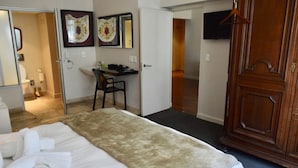 Une chambre d’hôtel équipée d’un lit, d’un bureau, d’une chaise, d’une armoire et d’un téléviseur fixé au mur.
