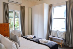 A hotel room with a bed, a wooden dresser, a bench by the window, and a wardrobe. - Heritage, Renovated 2 Bedroom Ponsonby Villa (Auckland)
