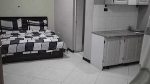 Un dormitori amb un llit, una cuineta petita i un bany.