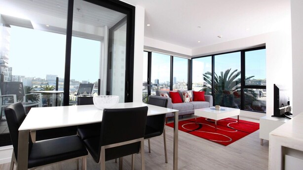 A modern living room with a dining area, large windows, and a city view. - 2 Bed Apt Heart of Ponsonby Gym (Auckland)