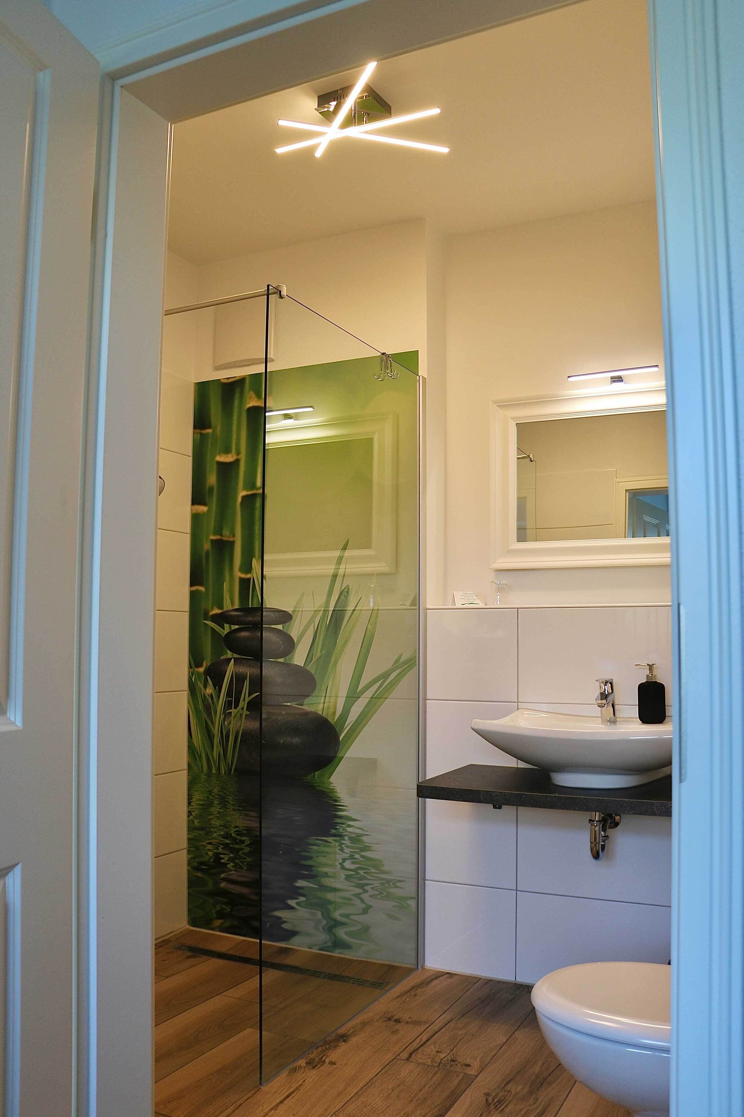 A modern bathroom with a glass shower enclosure, a sink, and a toilet.