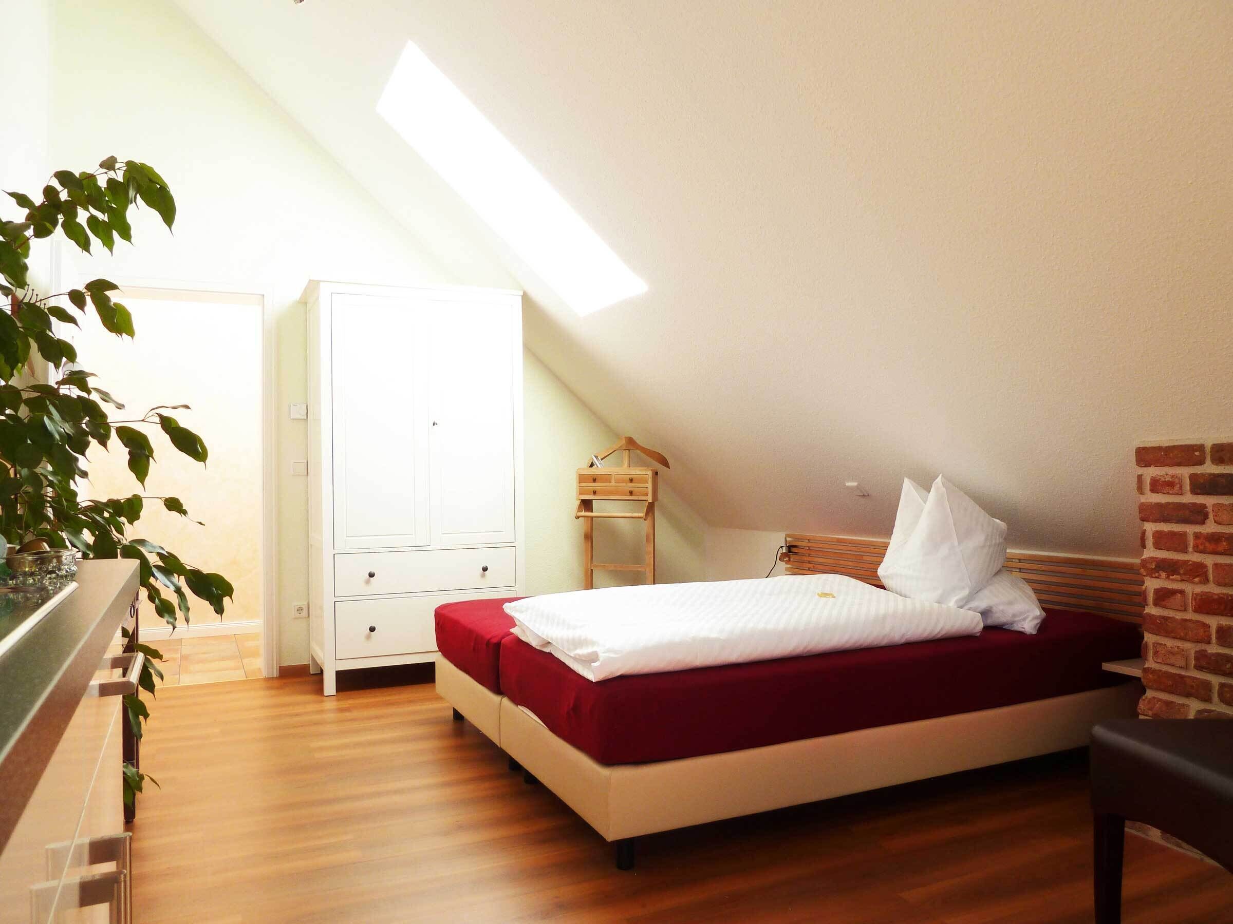 Ein Schlafzimmer mit einem Bett, einem Kleiderschrank, einer Pflanze und einer Ziegelwand.