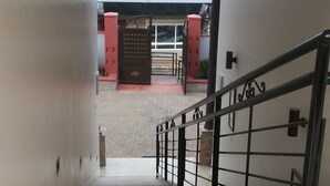 Una escalera conduce a un espacio exterior con una reja roja y un edificio con techo rojo.
