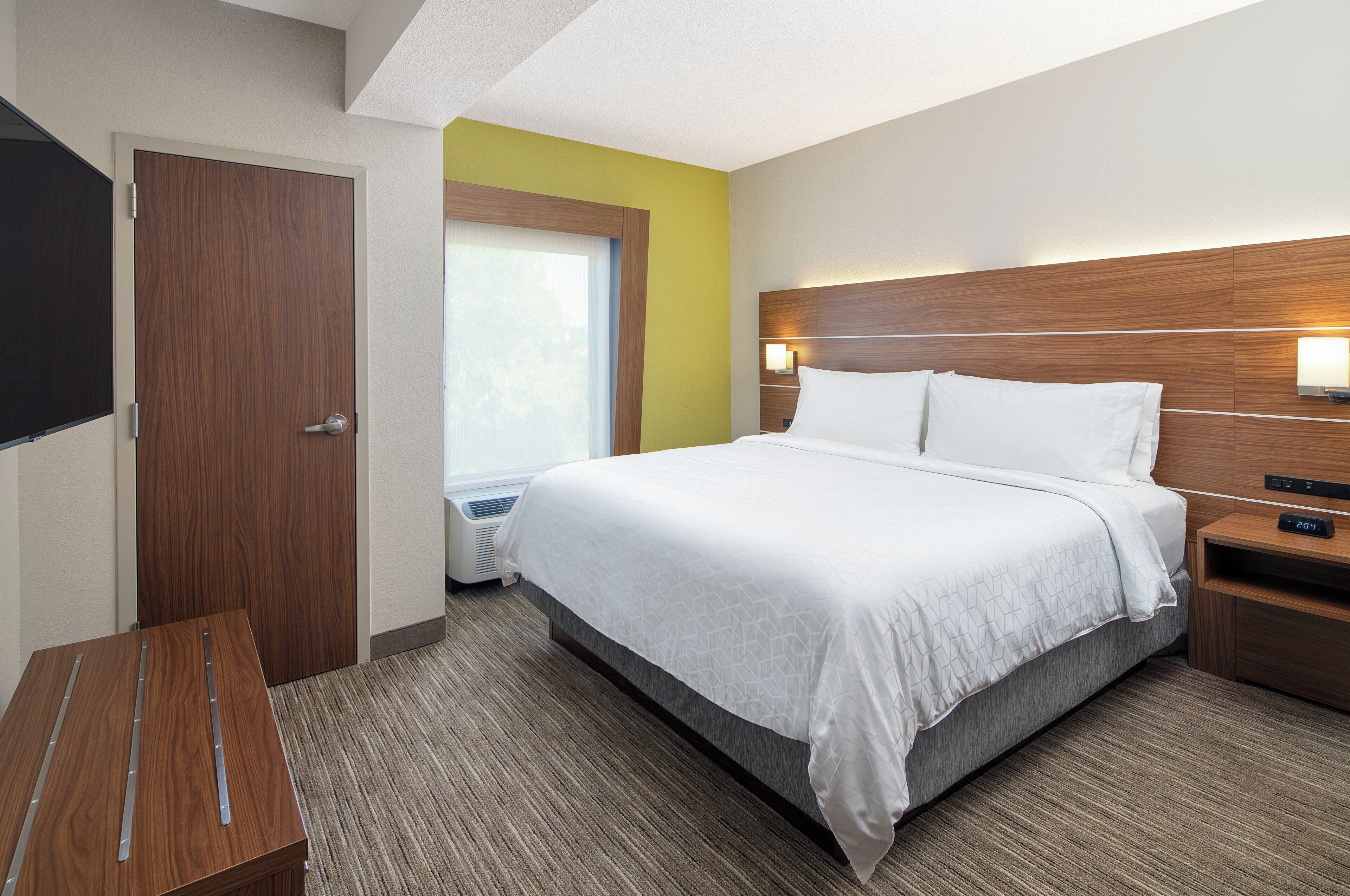 A hotel room with a bed, bedside table, and a television.