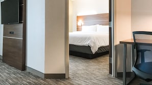 A hotel room with a bed, a television, and a desk with a chair.