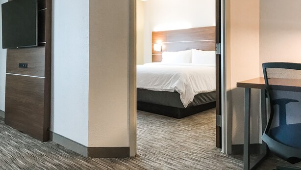 Una habitació d'hotel amb un llit, una televisió i un escriptori amb una cadira.