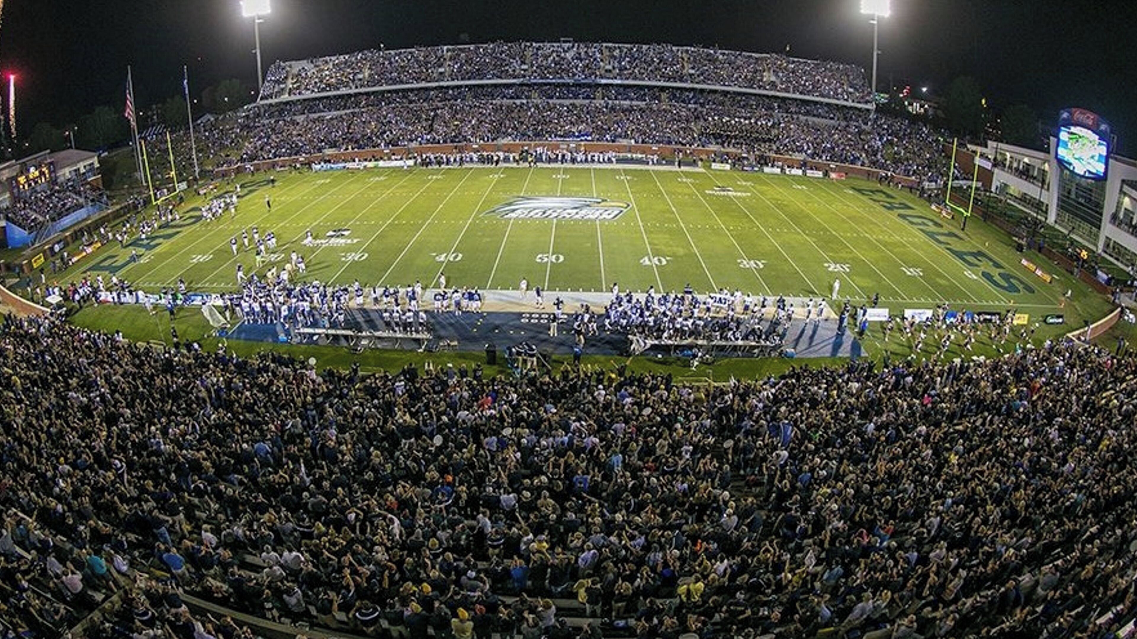 Un estadio grande con varios niveles de butacas, un campo de fútbol y una multitud de espectadores.