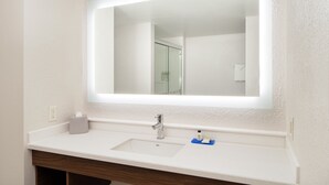 Un bany amb un lavabo blanc, un mirall i una tovallola penjada a la paret.
