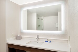 A bathroom with a white sink, a mirror, and a towel hanging on the wall. - Holiday Inn Express Statesboro by IHG (Statesboro)