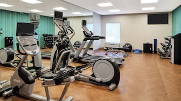 Un gimnasio con diversos equipos de ejercicio, incluyendo cintas de correr, elípticas y pesas libres.