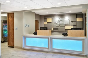 A hotel reception area with a modern design, including a reception desk, a vending machine, and a sign indicating the market is open 24 hours. - Holiday Inn Express Statesboro by IHG (Statesboro)