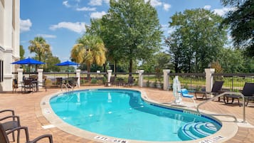 Una piscina al aire libre, sillones reclinables de piscina