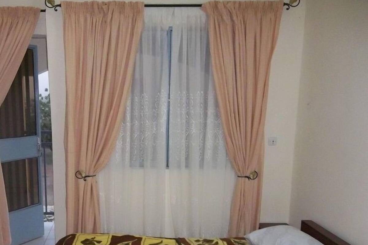 A bedroom with a bed, curtains, and a window.