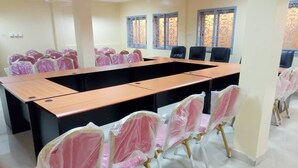 Une salle de conférence avec une longue table et des chaises, dont certaines sont recouvertes de plastique.