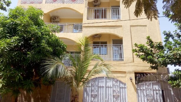 Un immeuble à plusieurs étages doté de balcons, d’une entrée sécurisée et entouré de verdure.
