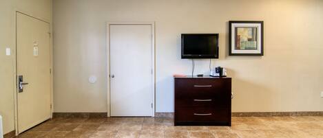 A hotel room with two beds, a TV, a dresser, and a door.