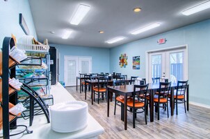 A dining area with tables and chairs, a counter with a basket, and an exit sign.
