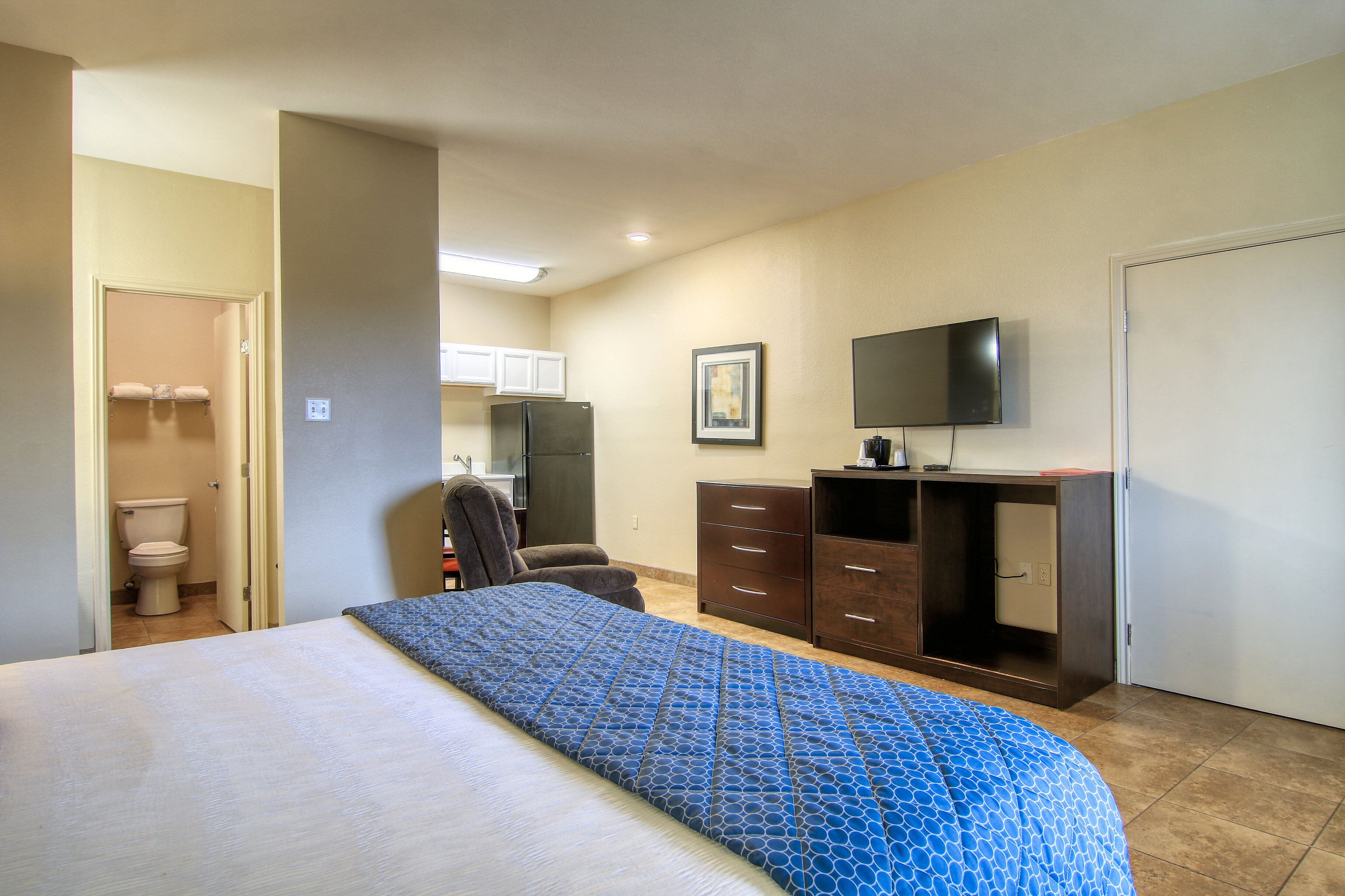 A hotel room with a bed, a desk, a chair, a television, and a wardrobe.