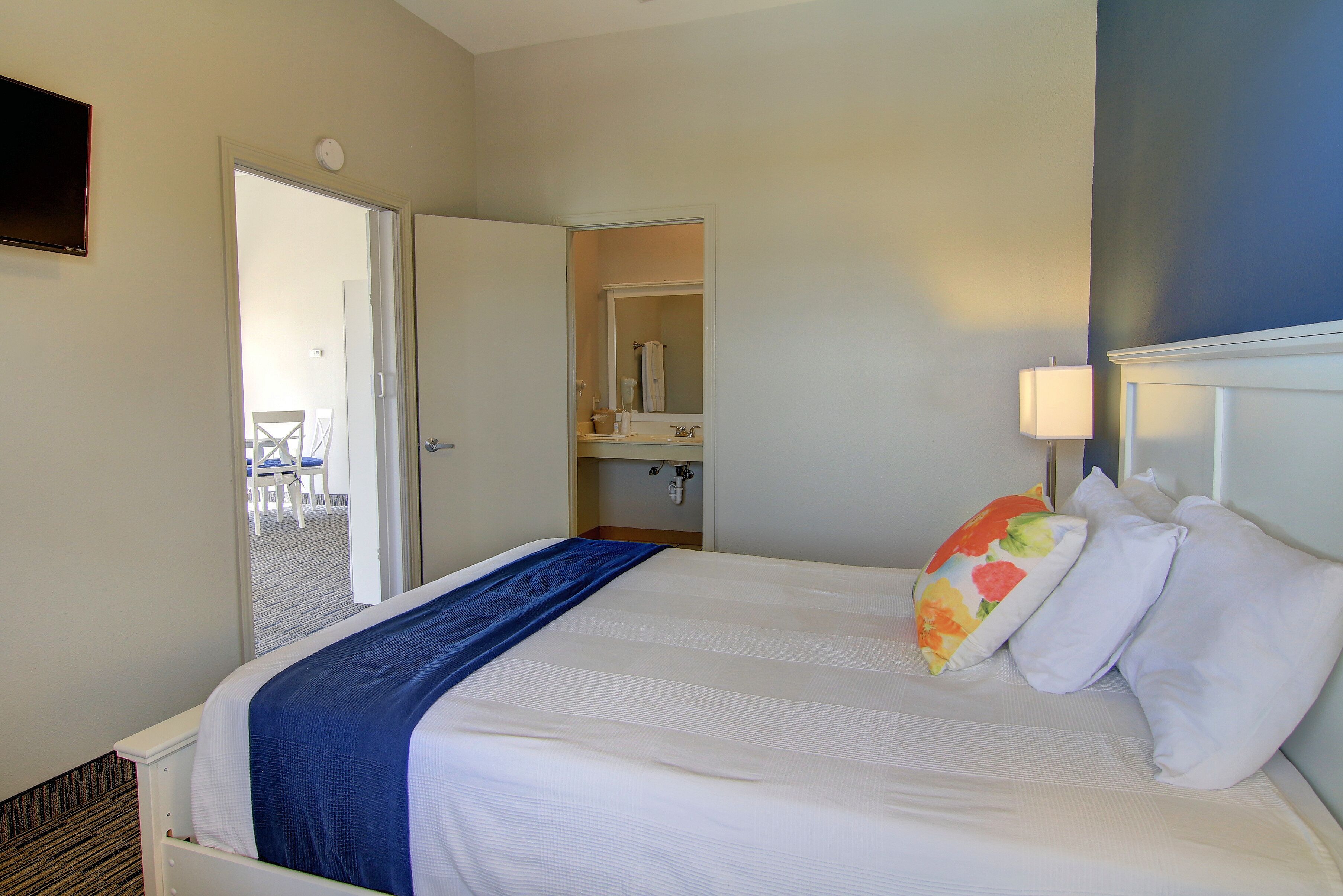 A hotel room with a bed, a bathroom, and a door leading to a balcony.