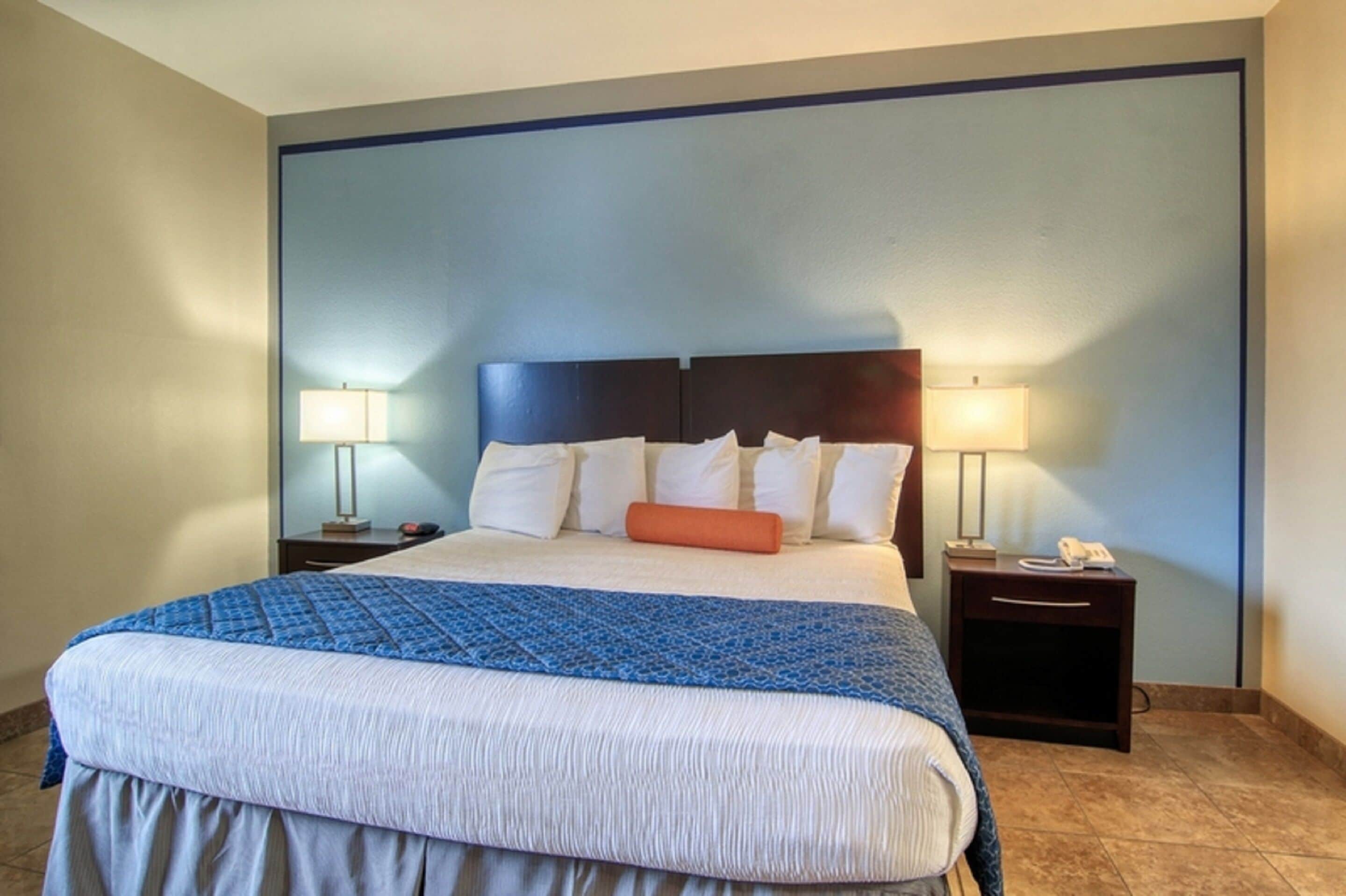 A hotel room with a large bed, two bedside tables, and lamps.