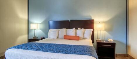 A hotel room with a large bed, two bedside tables, and lamps.
