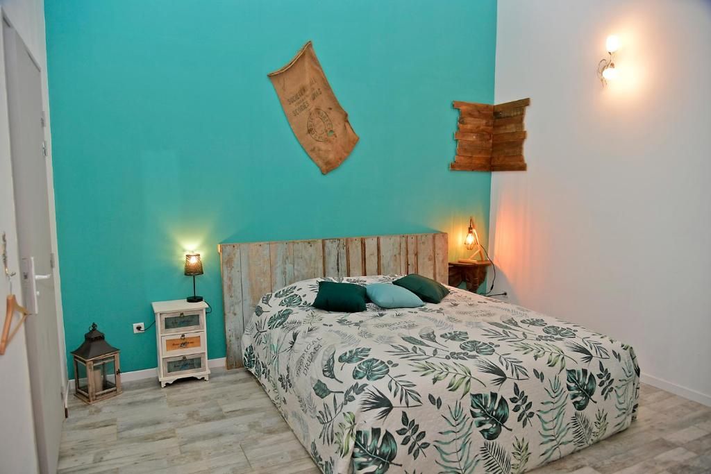 A bedroom with a teal wall, a wooden headboard, a bed with a floral bedspread, two bedside lamps, a small nightstand, and a wall-mounted light fixture.