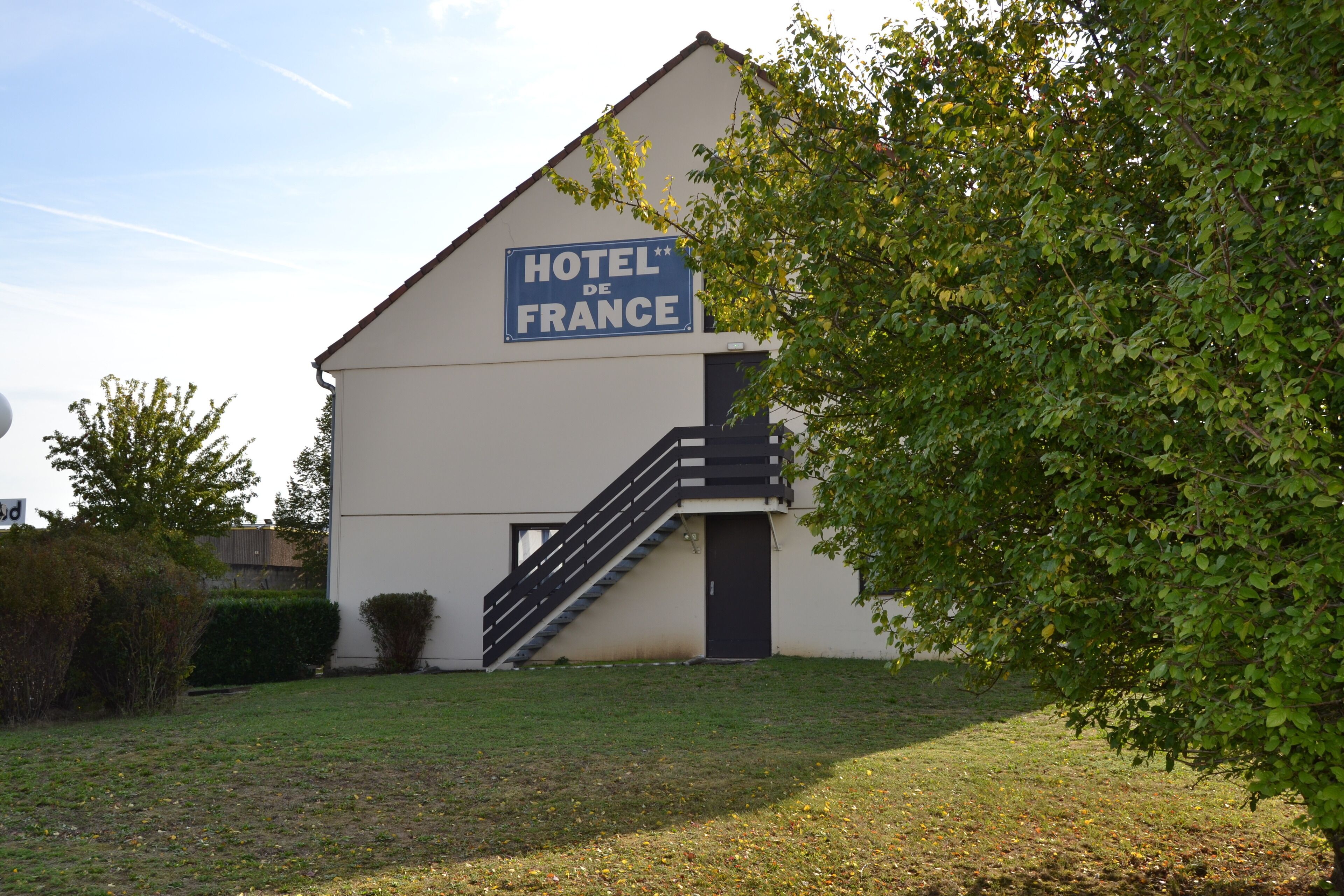 A building with a sign reading "HOTEL DE FRANCE" and a staircase leading to the entrance.