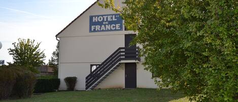 A building with a sign reading "HOTEL DE FRANCE" and a staircase leading to the entrance.