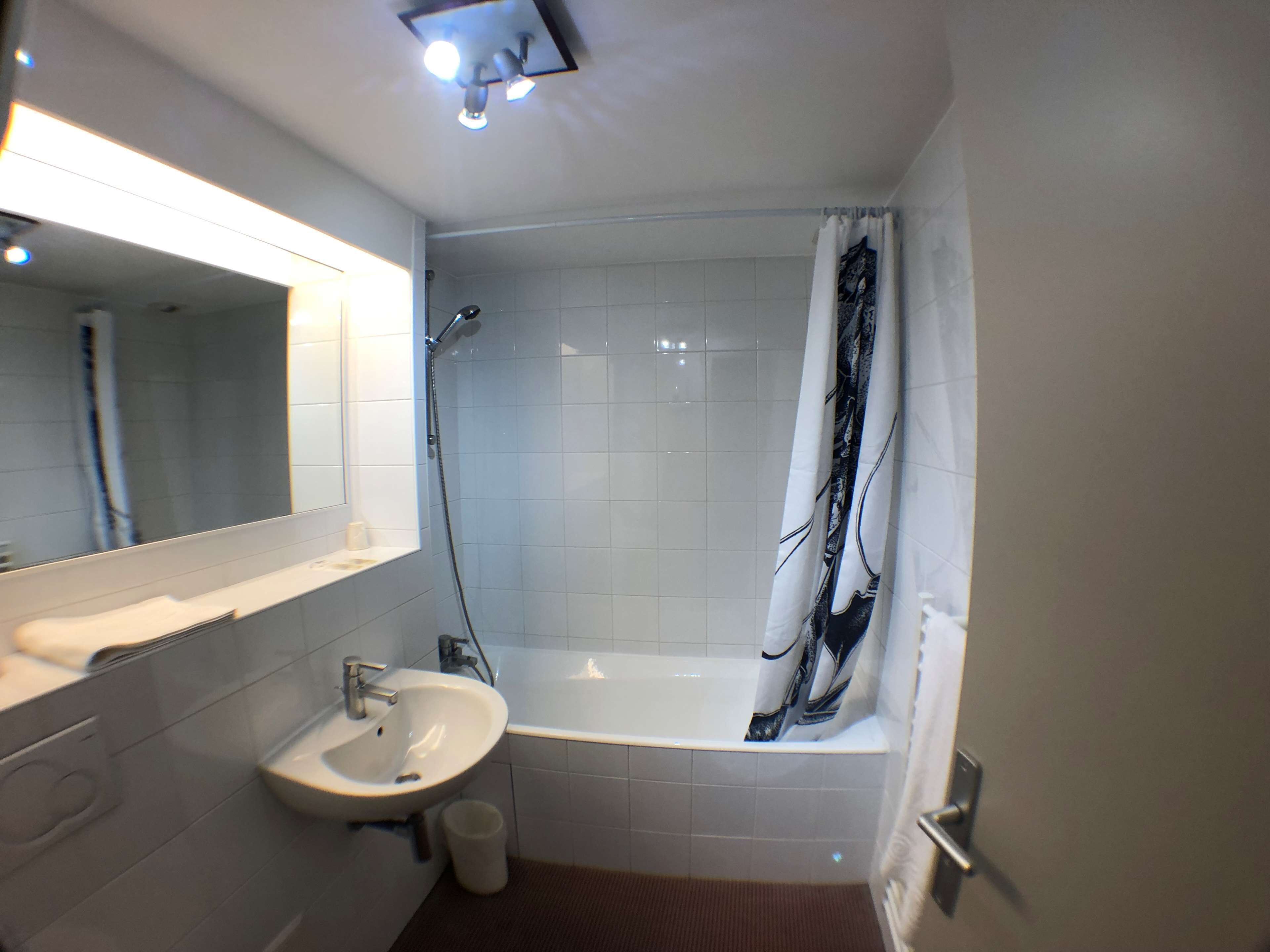 A bathroom with a sink, mirror, shower, and bathtub.