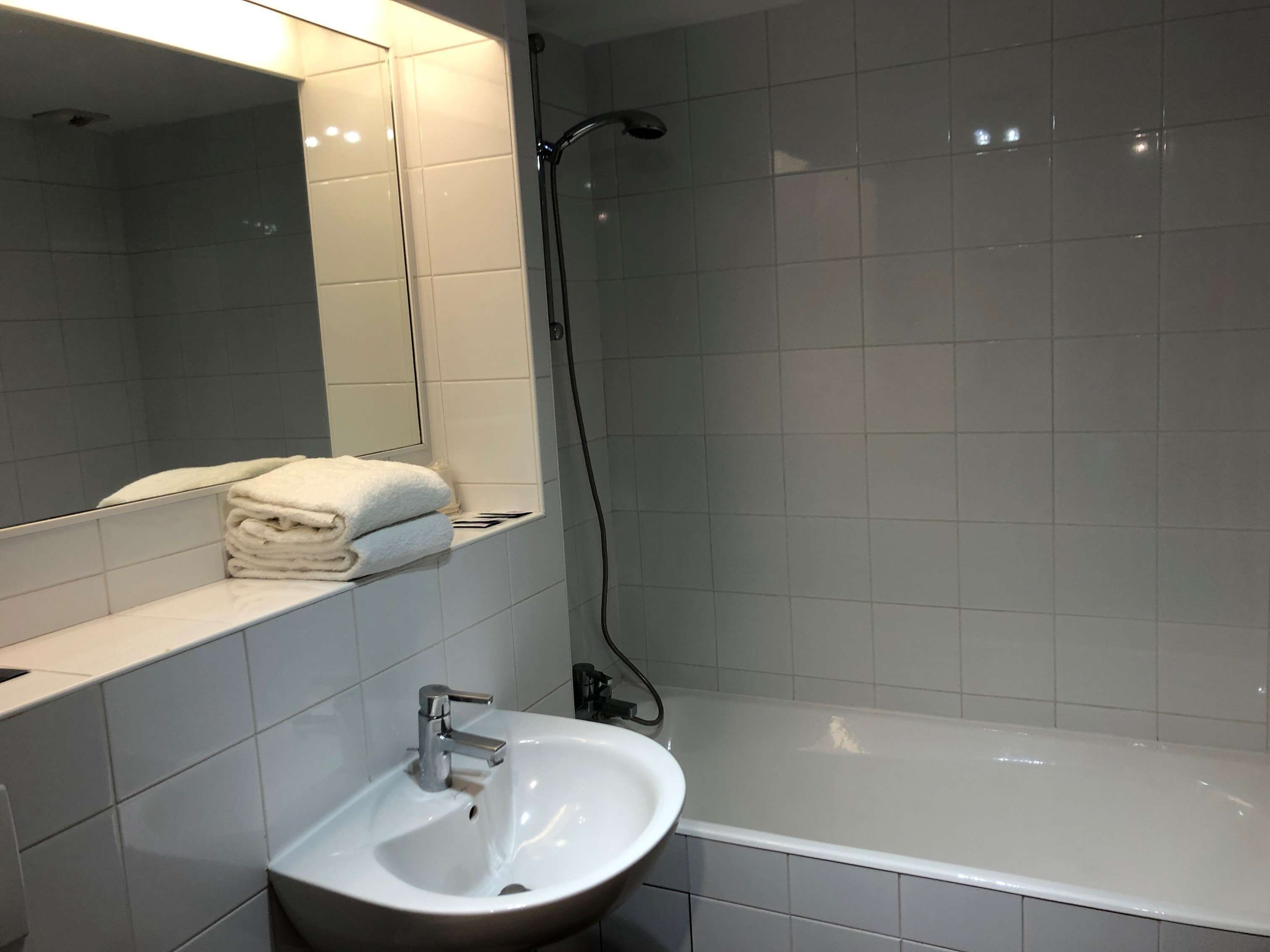 Ein Badezimmer mit Waschbecken, Spiegel und Duschbereich.