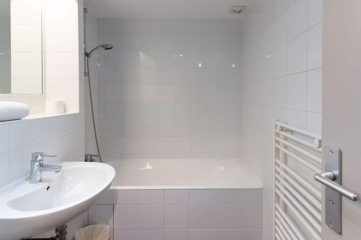 A bathroom with a white sink, a bathtub, and a shower.