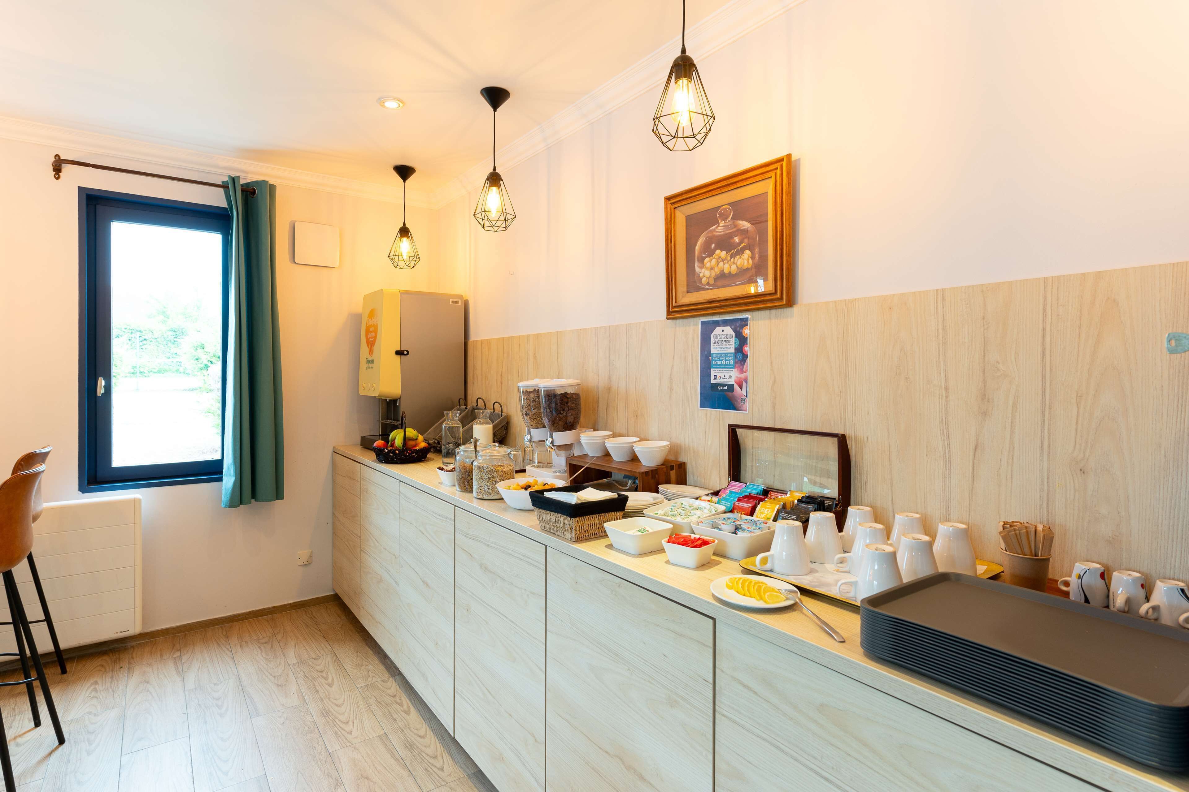 Una cocina moderna con barra desayunadora, armarios de madera y lámparas colgantes.