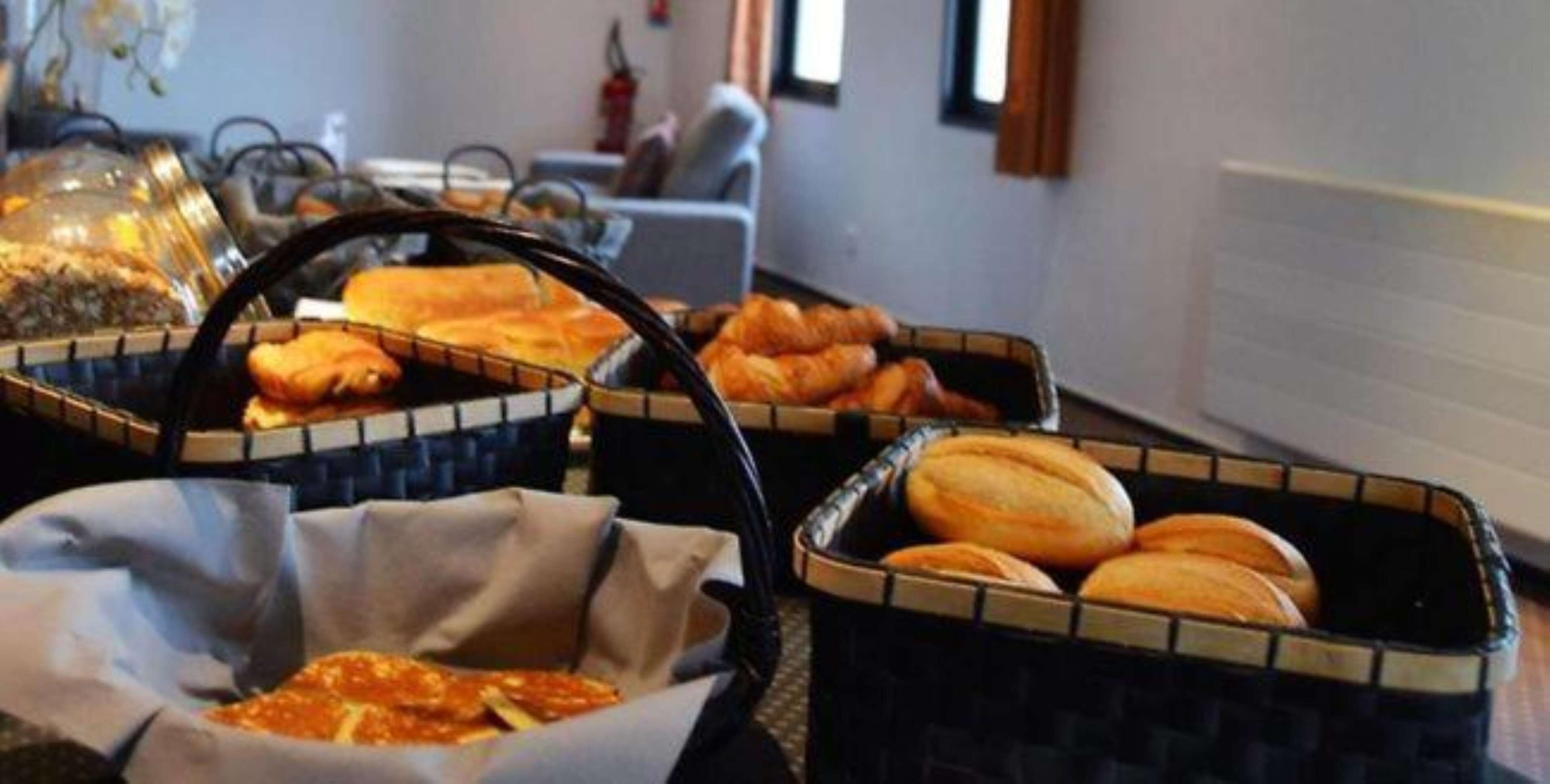 A buffet with various food items including bread and pastries in baskets.