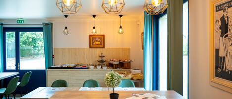 A dining area with a wooden table, green chairs, and hanging light fixtures.