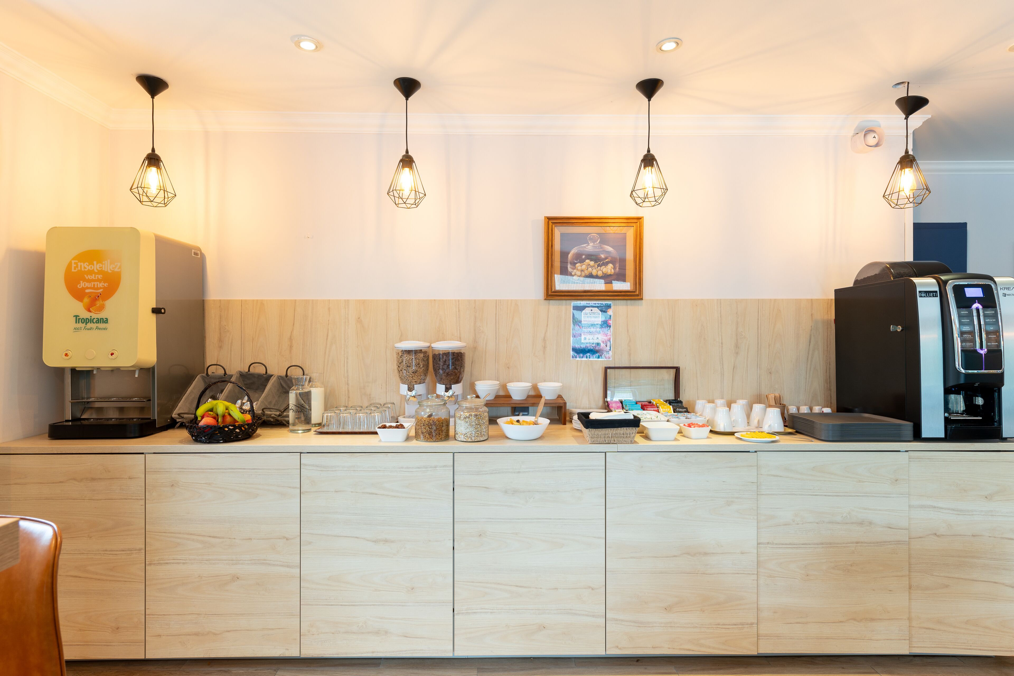 A modern kitchen area with a coffee machine, a fruit basket, and various food containers.