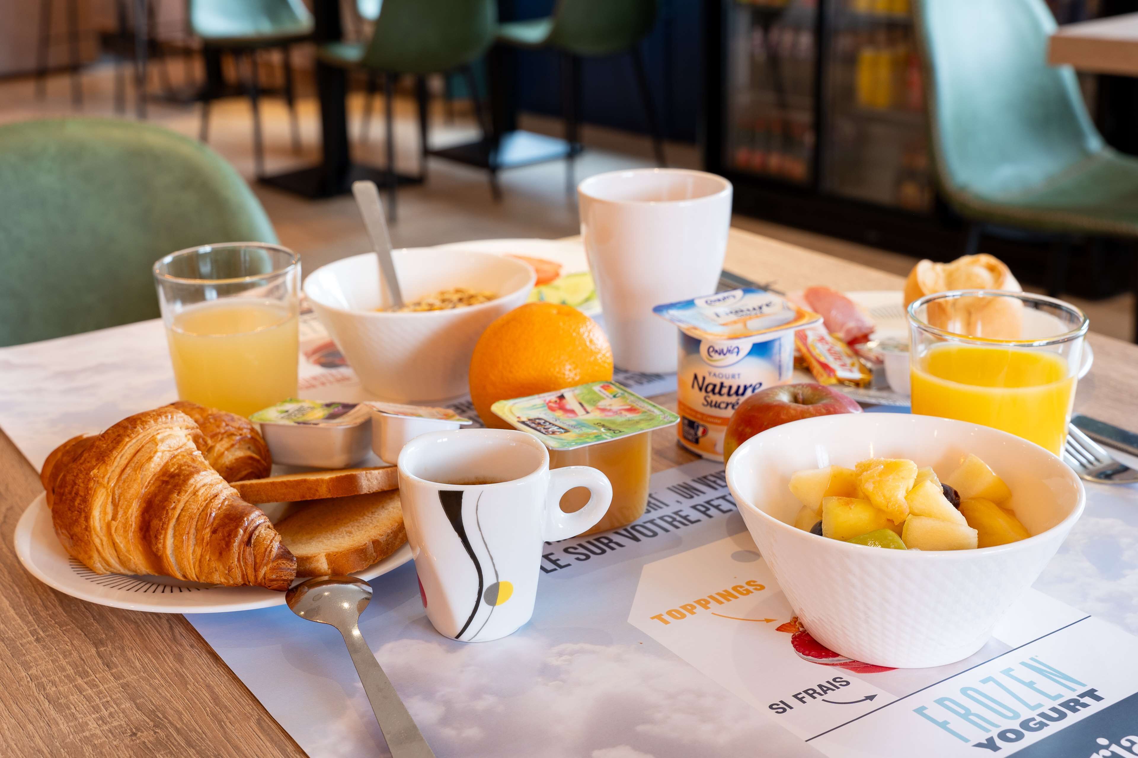 A breakfast table with croissants, fruit, yogurt, and juice.