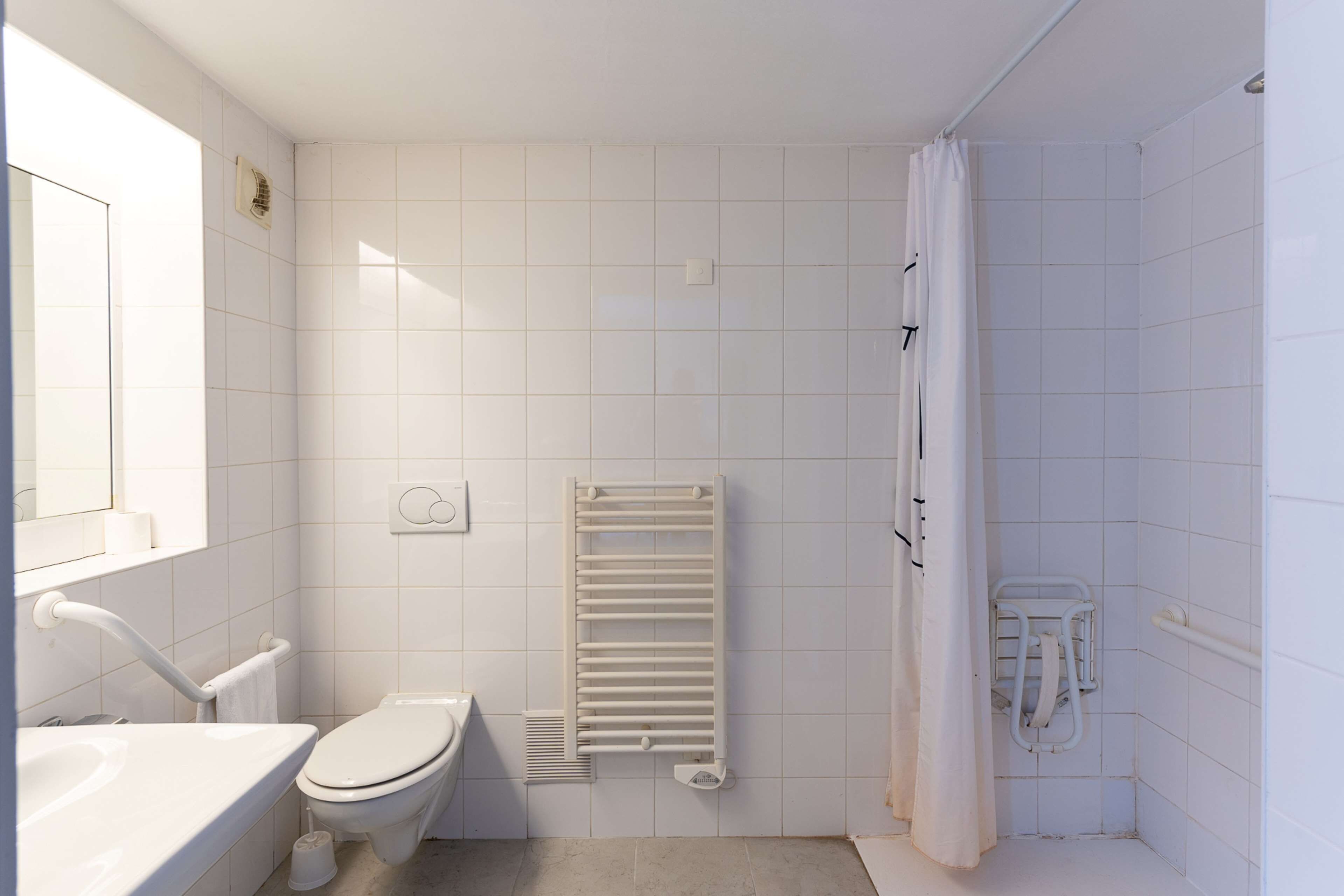 Un baño moderno con inodoro, lavamanos, ducha y toallero.