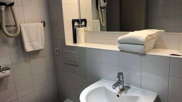Een badkamer met een witte wastafel, toilet, handdoekhouder, handdroger en spiegel.