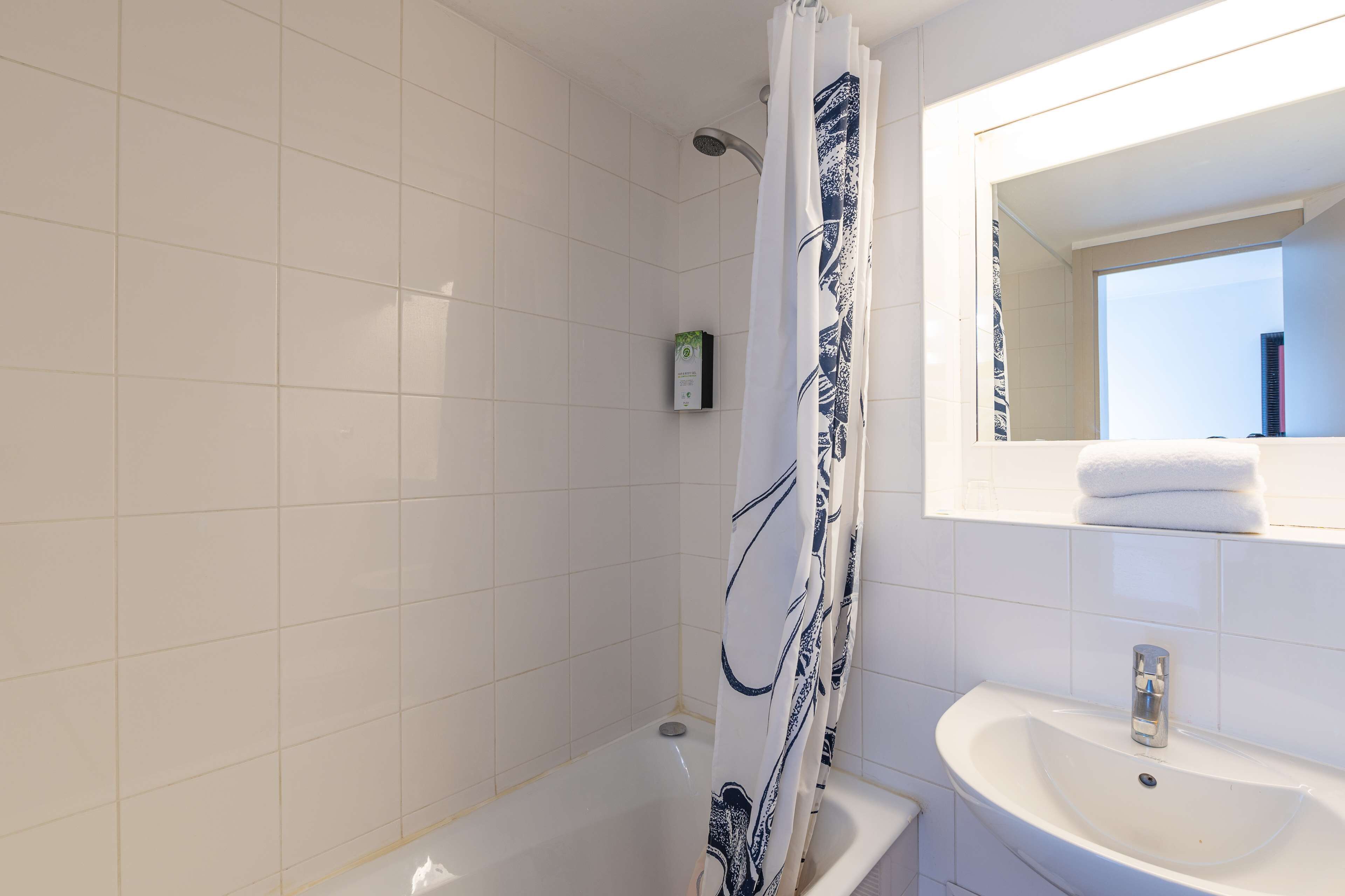 A bathroom with a shower, a sink, and a mirror.