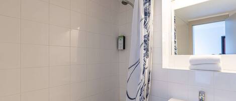A bathroom with a shower, a sink, and a mirror.