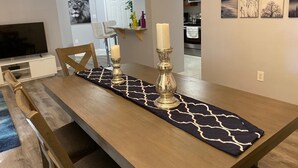 Un comedor con una mesa de madera, dos velas y un camino de mesa blanco y negro estampado.