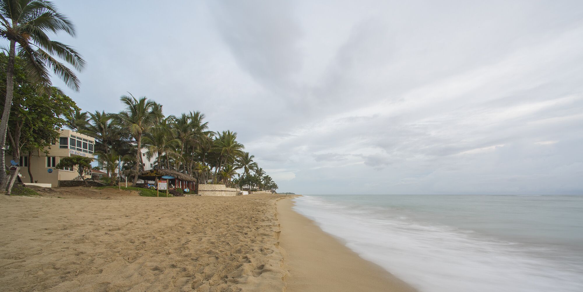 A beach with a hotel named "Kite Beach Inn" and palm trees.