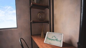 Une table en bois sur laquelle est posée une pancarte indiquant « TranquilNest » et un vase contenant des roseaux.